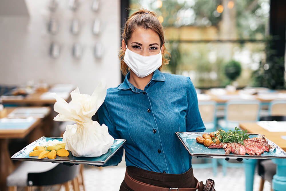 waitress wearing mask serving food